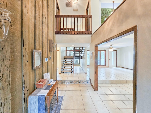 hallway with plenty of natural light, a high ceiling, and light tile patterned floors