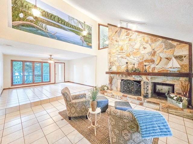 tiled living room with rail lighting, ceiling fan, a textured ceiling, and a fireplace