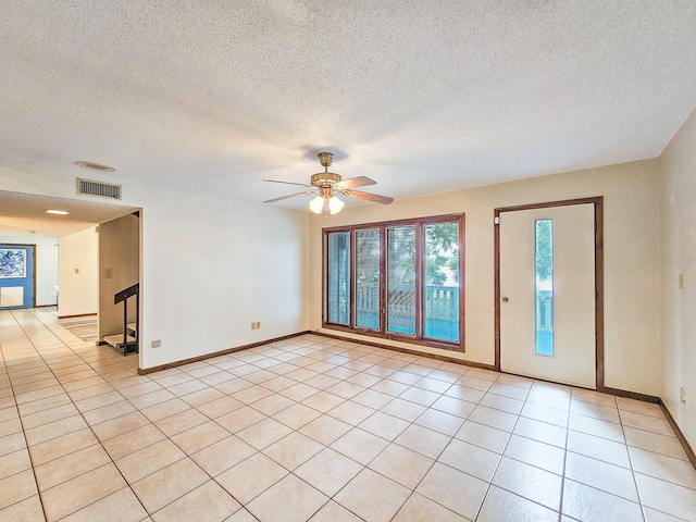 tiled empty room featuring a textured ceiling and ceiling fan