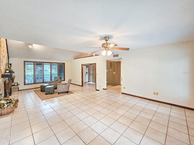 unfurnished living room with vaulted ceiling, a textured ceiling, light tile patterned floors, ceiling fan, and a fireplace