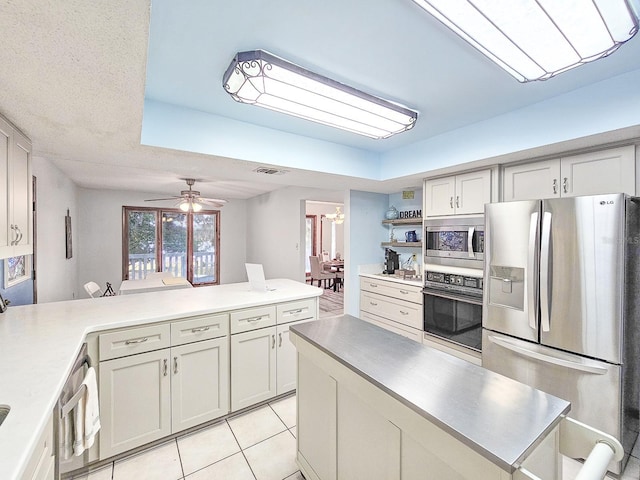 kitchen featuring light tile patterned floors, kitchen peninsula, ceiling fan, and appliances with stainless steel finishes