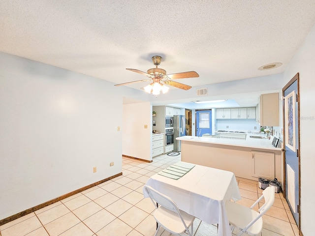 kitchen with light tile patterned flooring, kitchen peninsula, and a textured ceiling