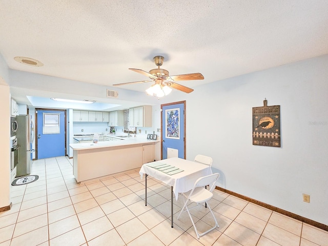 tiled dining area featuring ceiling fan, sink, and a textured ceiling