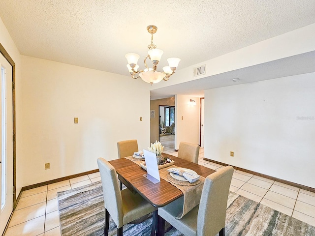 dining area with light tile patterned floors, a textured ceiling, and a chandelier