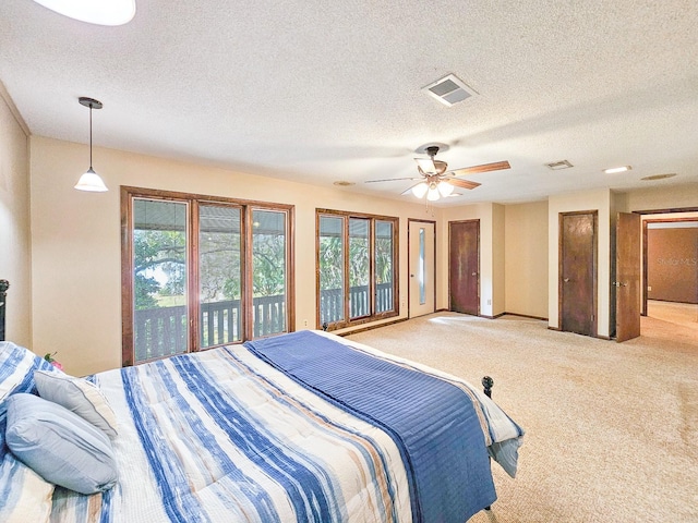 bedroom with ceiling fan, light colored carpet, and a textured ceiling