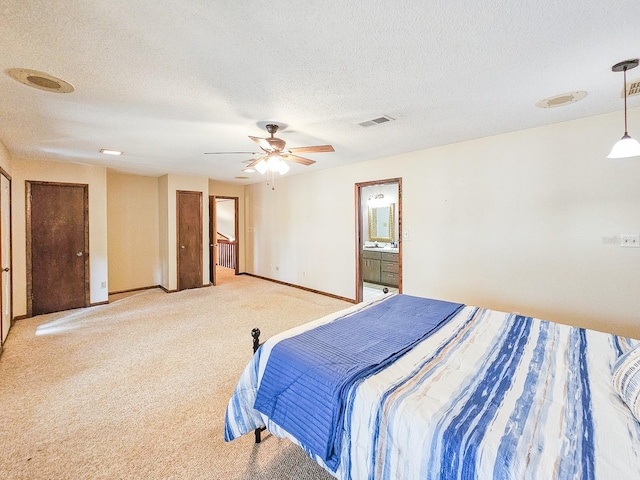 bedroom featuring ceiling fan, connected bathroom, light carpet, and a textured ceiling