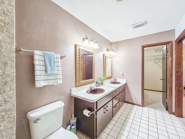 bathroom with vanity, tile patterned floors, toilet, and a textured ceiling