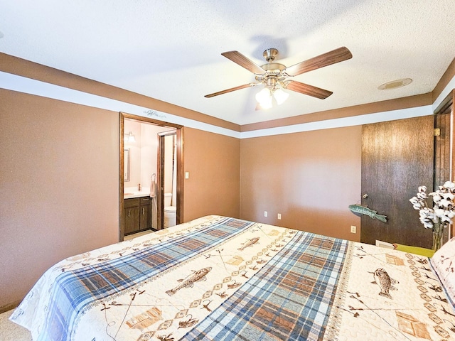 bedroom with ceiling fan, connected bathroom, and a textured ceiling