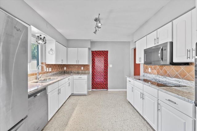 kitchen with light stone countertops, appliances with stainless steel finishes, backsplash, sink, and white cabinetry