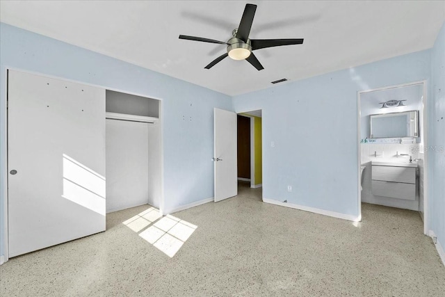 unfurnished bedroom with ceiling fan, ensuite bathroom, and a closet