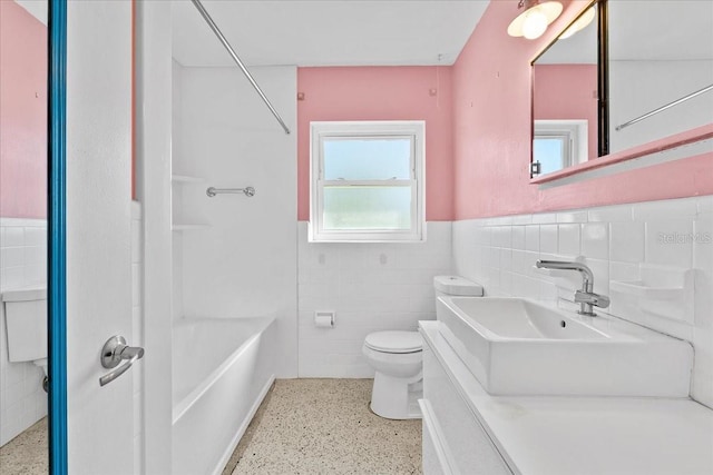 bathroom with toilet, tile walls, and sink