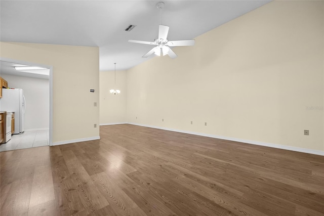 unfurnished room featuring ceiling fan with notable chandelier, lofted ceiling, and light hardwood / wood-style flooring