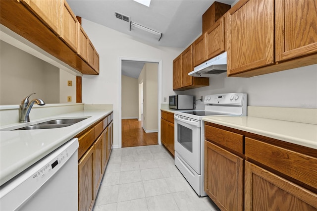 kitchen with white appliances, sink, and vaulted ceiling