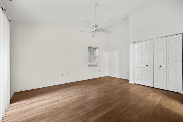 unfurnished bedroom featuring hardwood / wood-style flooring, ceiling fan, high vaulted ceiling, and a closet