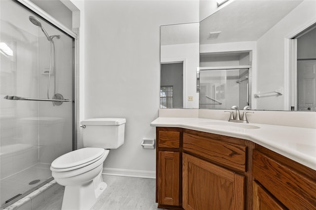 bathroom with vanity, toilet, and a shower with door