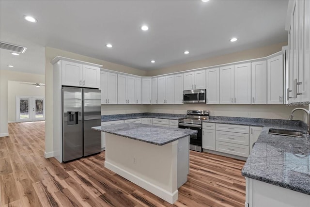 kitchen with light wood finished floors, visible vents, white cabinets, stainless steel appliances, and a sink