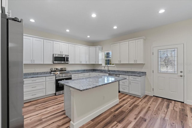 kitchen with appliances with stainless steel finishes, recessed lighting, white cabinets, and light wood-style floors