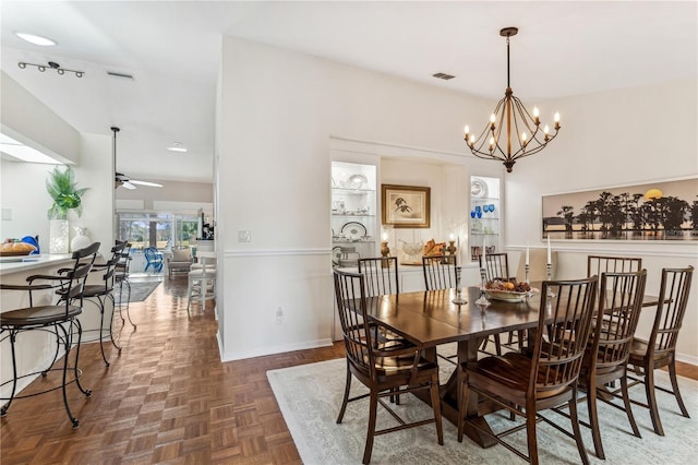 dining space featuring dark parquet flooring and ceiling fan with notable chandelier