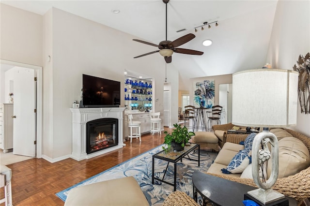 living room featuring dark parquet flooring, vaulted ceiling, and ceiling fan