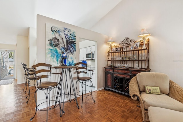 bar featuring dark parquet floors and vaulted ceiling