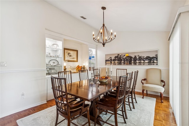 dining area with light parquet flooring, a chandelier, and lofted ceiling