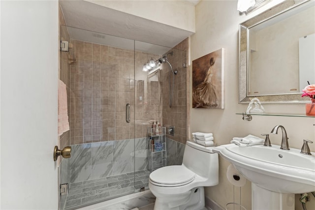 bathroom featuring toilet, a shower with shower door, and sink