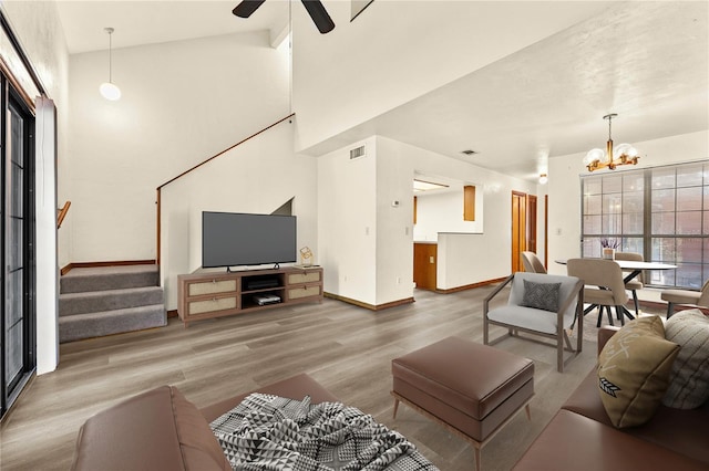 living room with hardwood / wood-style flooring, ceiling fan with notable chandelier, and high vaulted ceiling