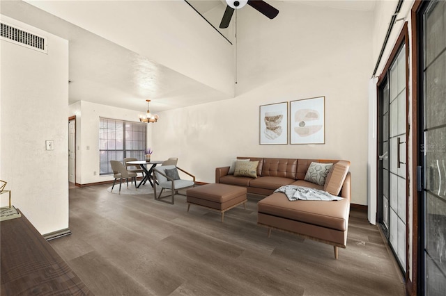 living room featuring a towering ceiling, ceiling fan with notable chandelier, and dark hardwood / wood-style floors