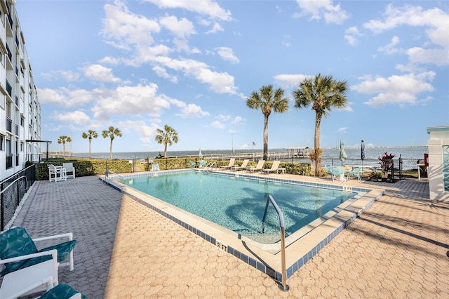 view of pool featuring a water view and a patio area