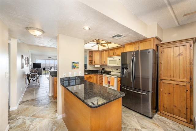 kitchen featuring white appliances, dark stone counters, ceiling fan, a textured ceiling, and kitchen peninsula