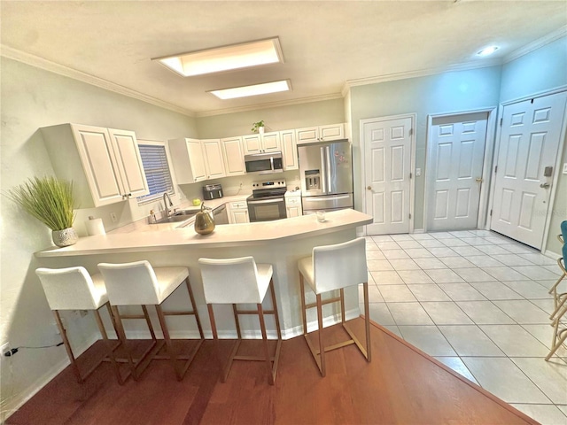 kitchen with a breakfast bar area, kitchen peninsula, white cabinets, and stainless steel appliances