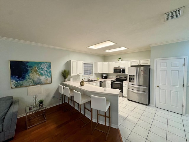 kitchen with crown molding, white cabinetry, kitchen peninsula, and appliances with stainless steel finishes