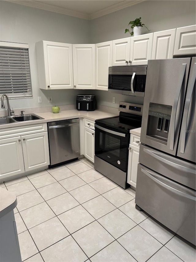 kitchen with white cabinetry, sink, appliances with stainless steel finishes, light tile patterned flooring, and ornamental molding