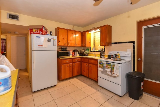 kitchen with decorative backsplash, light tile patterned floors, white appliances, and sink