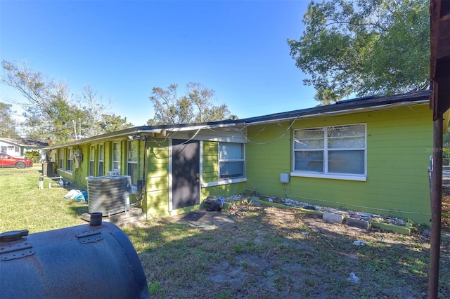 view of side of property featuring a yard and central AC