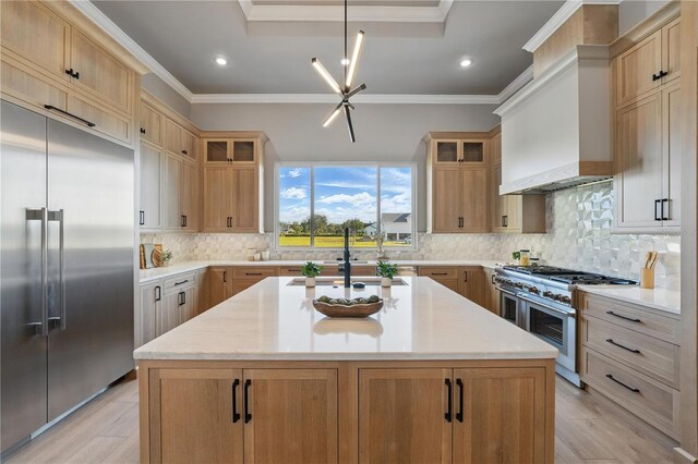 5040 SW 125th Cir, Archer, FL 32618 - kitchen featuring high end appliances, ornamental molding, wall chimney range hood, glass insert cabinets, and a center island