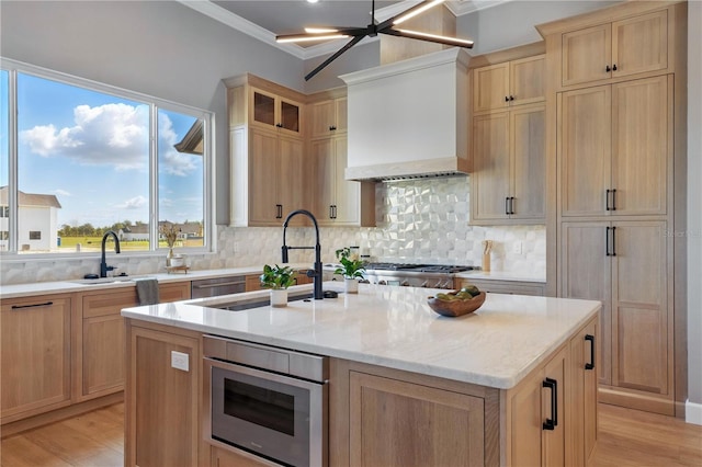 5040 SW 125th Cir, Archer, FL 32618 - kitchen with custom range hood, an island with sink, light wood finished floors, light stone counters, and crown molding