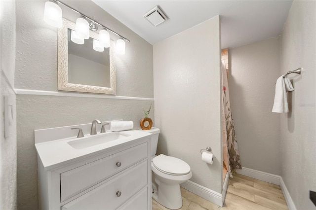 bathroom featuring hardwood / wood-style floors, vanity, toilet, and walk in shower