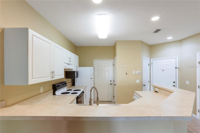 kitchen with kitchen peninsula, white appliances, sink, light tile patterned floors, and white cabinetry