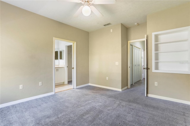 carpeted empty room featuring ceiling fan and built in features