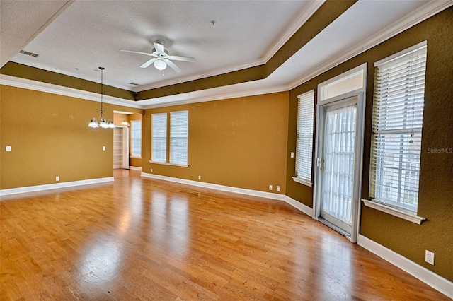 spare room featuring crown molding, ceiling fan with notable chandelier, light hardwood / wood-style floors, and a raised ceiling