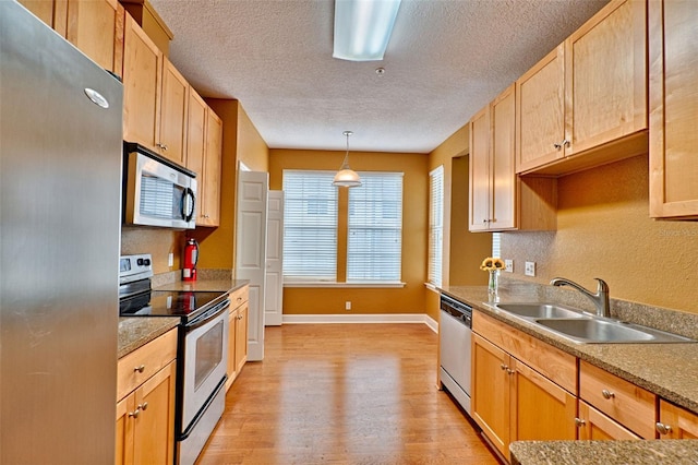 kitchen featuring sink, a textured ceiling, light wood-type flooring, appliances with stainless steel finishes, and pendant lighting