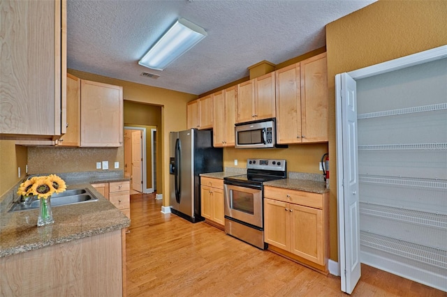 kitchen with stainless steel appliances, light wood-type flooring, and light brown cabinets