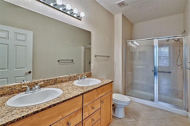 bathroom featuring tile patterned flooring, toilet, a shower with door, and a textured ceiling