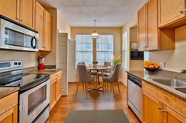 4715 SW 91st Dr Unit 305, Gainesville, FL 32608 - kitchen with appliances with stainless steel finishes, light wood-type flooring, a textured ceiling, and hanging light fixtures