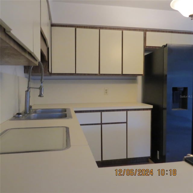 kitchen featuring white cabinetry, black fridge with ice dispenser, and sink