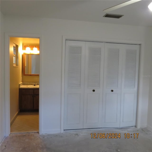 unfurnished bedroom with ceiling fan, a closet, sink, and ensuite bath