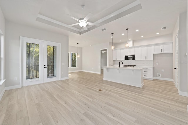 kitchen featuring white cabinets, a raised ceiling, ceiling fan, decorative light fixtures, and light hardwood / wood-style floors