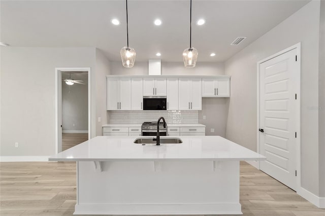 kitchen featuring pendant lighting, a kitchen island with sink, sink, and appliances with stainless steel finishes