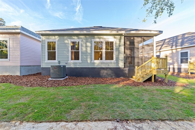 view of side of home with a sunroom, central air condition unit, and a lawn